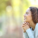Smiling woman with curly hair relaxing outdoors in natural sunlight