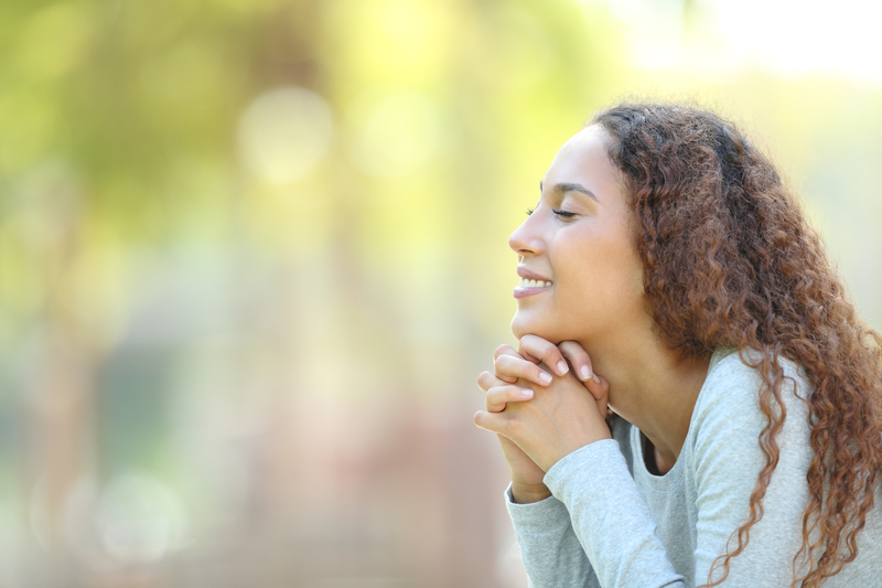 Smiling woman with curly hair relaxing outdoors in natural sunlight