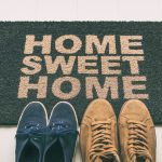 Entry mat that says home sweet home with 2 pairs of shoes in front.