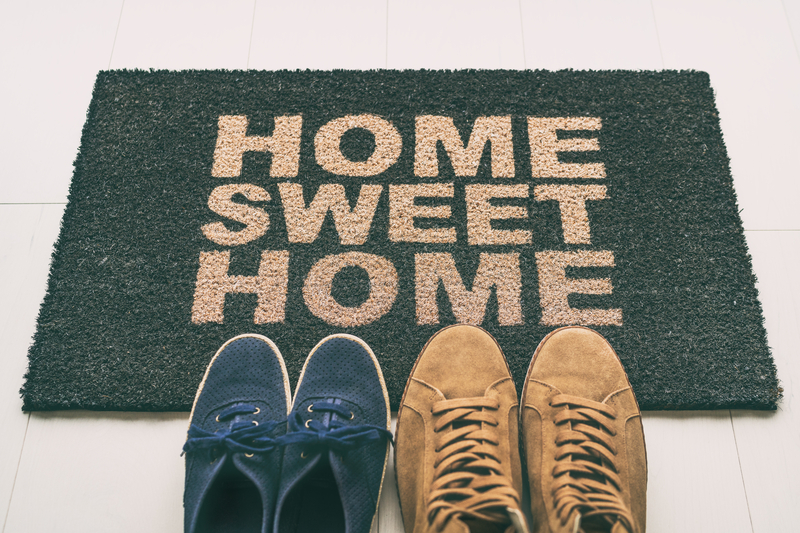 Entry mat that says home sweet home with 2 pairs of shoes in front.