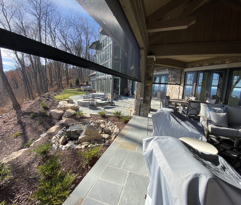 Custom retractable screens enclosing a outdoor porch with stone columns in South Carolina