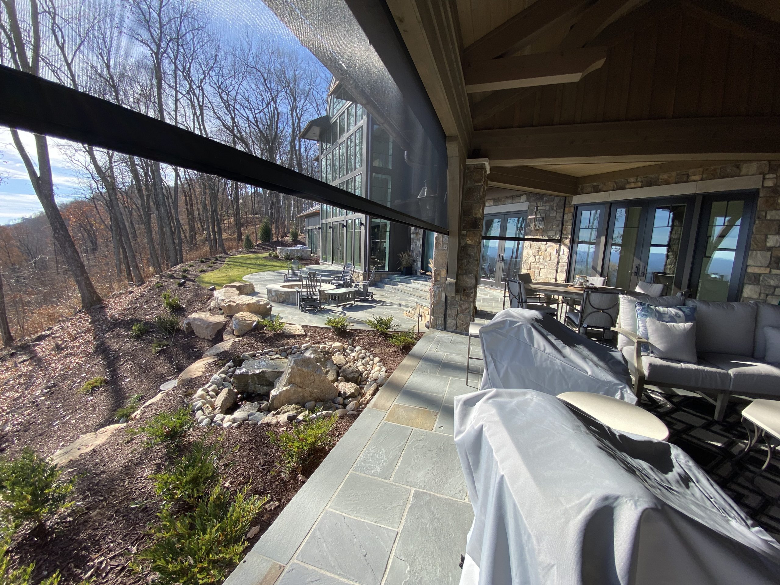 Custom retractable screens enclosing a outdoor porch with stone columns in South Carolina